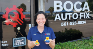 jeep repair and maintenance in boca raton, fl. image of alissa, co-owner of boca auto fix in boca raton, fl, standing in front of the shop holding two rubber ducks, symbolizing the shop's participation in the jeep ducking trend.