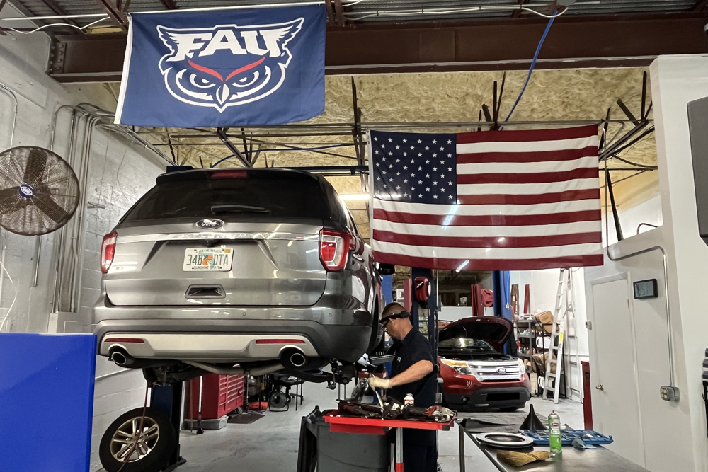 ford repair services in boca raton, fl – your trusted ford specialists with boca auto fix. image of mechanic and owner doug deluca working on a newer ford explorer on a lift for ford brake repair services.