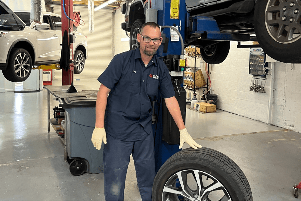 tire rotation services, auto repair in boca raton, fl at boca auto fix. a mechanic holding a tire, showcasing professional and reliable tire maintenance services.