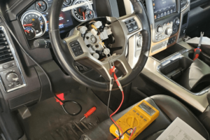 car diagnostic, auto repair in Boca Raton, FL at Boca Auto Fix. Interior view of a vehicle undergoing diagnostic testing with a multimeter connected to the steering column.