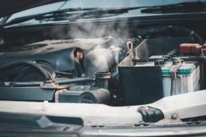 cooling system check, auto repair in Boca Raton, FL at Boca Auto Fix. Overheating engine with steam rising from the radiator area. Image taken with the hood open, showing a common cooling system failure.