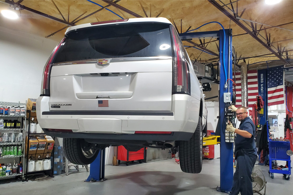 Cadillac Auto Repair in Boca Raton, FL - Boca Auto Fix Cadillac auto repair in Boca Raton, FL at Boca Auto Fix. A white Cadillac SUV on lift inside an auto repair shop.