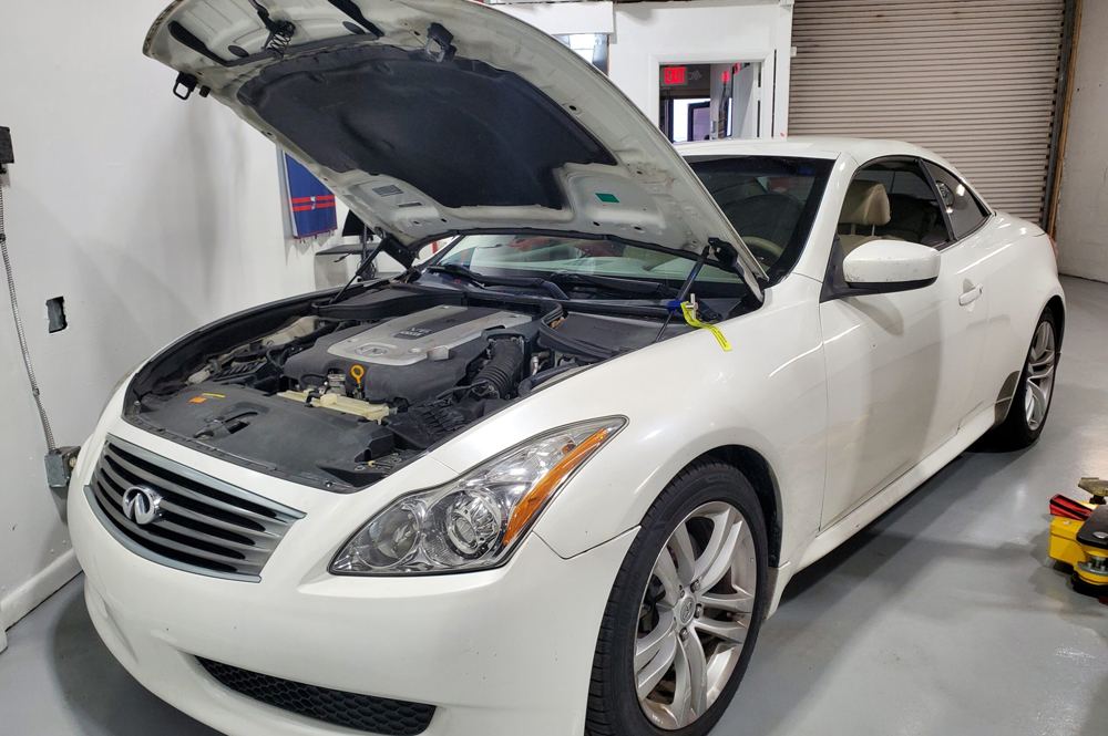 Infiniti Auto Repair in Boca Raton, FL - Boca Auto Fix Infiniti auto repair in Boca Raton, FL at Boca Auto Fix. A white Infiniti vehicle with the hood open inside an auto repair shop.