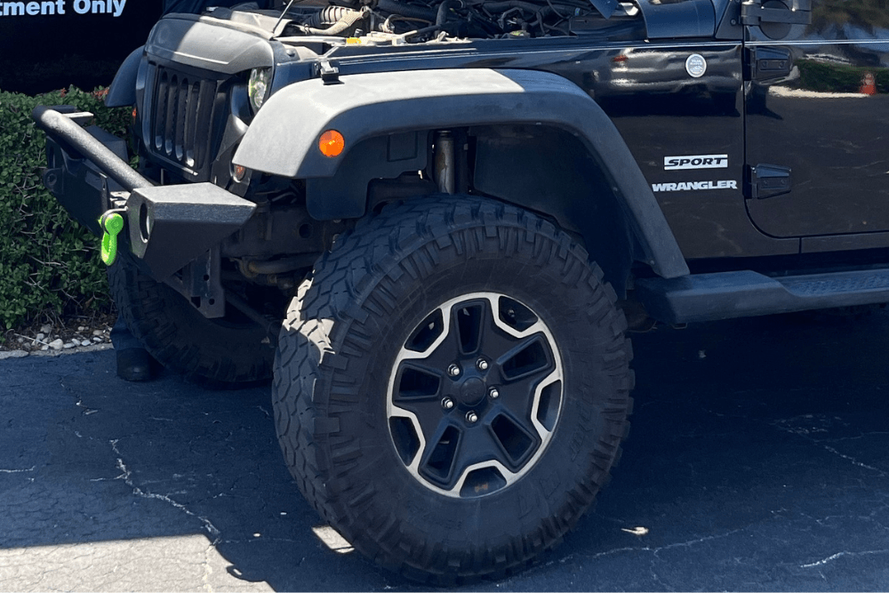tire safety, Tire services in Boca Raton, FL by Boca Auto Fix. Image of a black Jeep Wrangler Sport with off-road tires, highlighting the shop’s commitment to performance, durability, and reliability for Jeep owners.