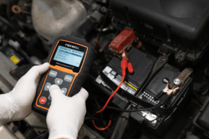 Car battery replacement in Boca Raton, FL by Boca Auto Fix. Image showing a mechanic using a diagnostic tool to test a car battery’s performance, ensuring reliable starts and preventing unexpected electrical issues.