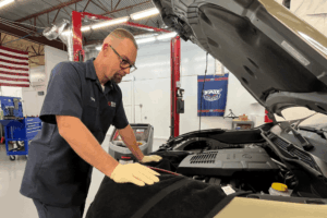 Trusted mechanic, auto repair in Boca Raton, FL by Boca Auto Fix. Image of Doug DeLucca inspecting an engine bay with the hood open inside the shop, highlighting professional diagnostics and hands-on engine maintenance to ensure reliable vehicle performance.