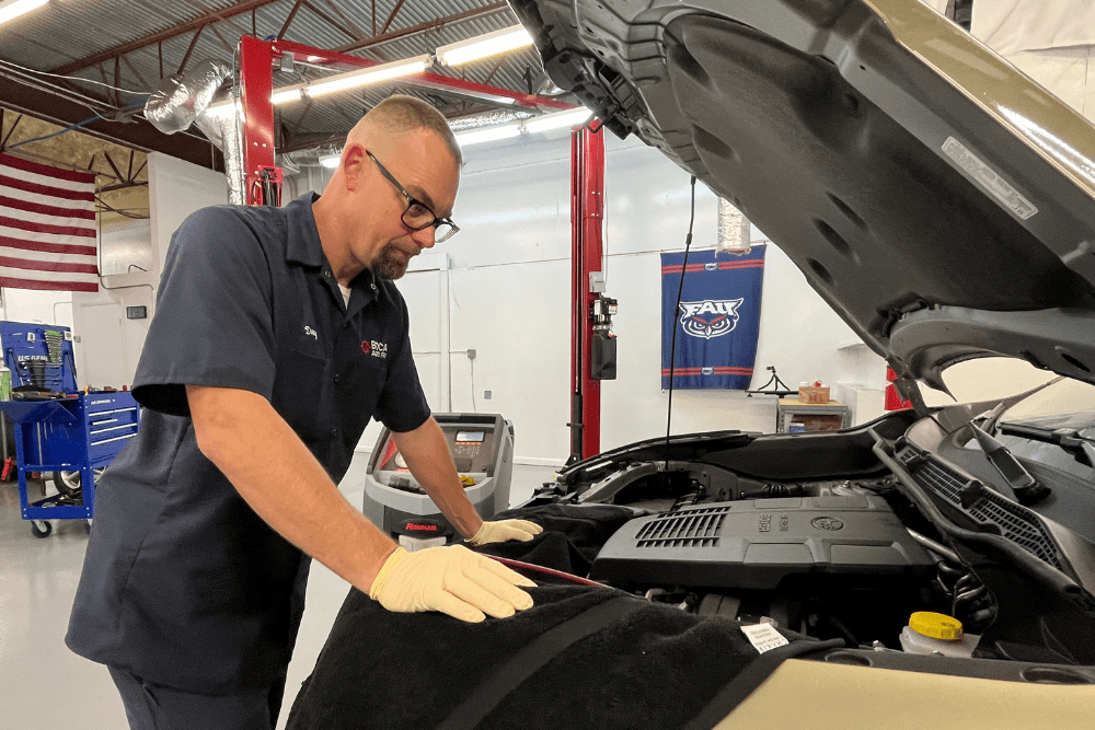Trusted mechanic, auto repair in Boca Raton, FL by Boca Auto Fix. Image of Doug DeLucca inspecting an engine bay with the hood open inside the shop, highlighting professional diagnostics and hands-on engine maintenance to ensure reliable vehicle performance.