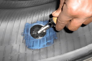 Tire Repair in Boca Raton, FL at Boca Auto Fix. An image of a hand uses a wooden-handled tire repair tool to pull the metal stem of a patch-plug through a blue and black patch on the tire's inner lining.