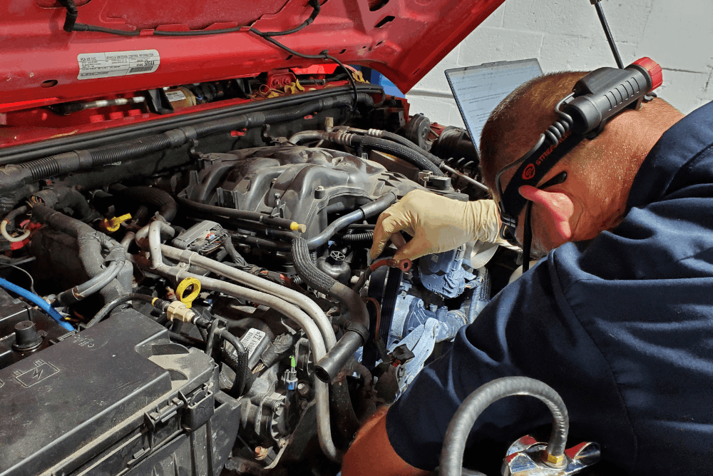Cooling system repair and car overheating fix, auto repair in Boca Raton, FL, at Boca Auto Fix. Image of Doug DeLucca performing engine diagnostics and repair under the hood of a vehicle using professional diagnostic equipment in an auto repair shop.
