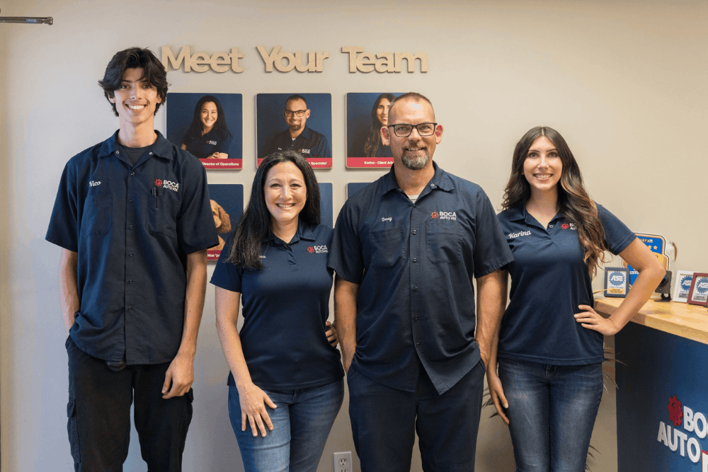 image of doug & alissa delucca and staff members standing inside the shop in front of a meet your team display and service awards.