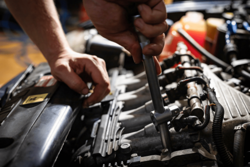 Boca Auto Fix – fuel system repair 1-min fuel system repair, auto repair in Boca Raton, FL at Boca Auto Fix. Image of a mechanic tightening components on a fuel rail with a socket wrench under the hood